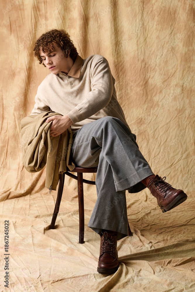 Naklejka premium Stylish teenager in casual fashion poses elegantly on a wooden chair
