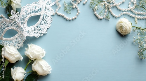 Elegant white lace masquerade mask and fresh flowers arranged on pale blue background for celebratory invitation