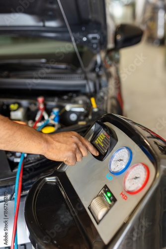 Mechanic checking the car air conditioning system using a technological diagnostic device.