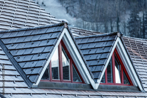 Foto Detail shot of a home with a weathered roof, dormer windows, and a snowy landscape
