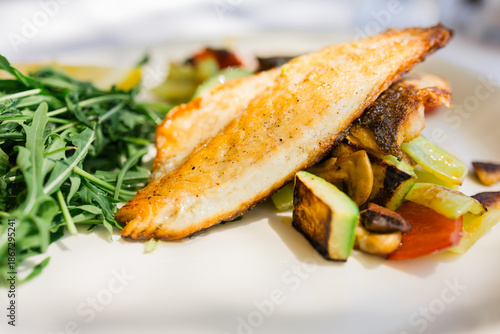 Grilled fish fillet with vegetables served on restaurant plate. Healthy nutrition, balanced diet choices and mindful dining habits supporting modern lifestyle wellbeing.