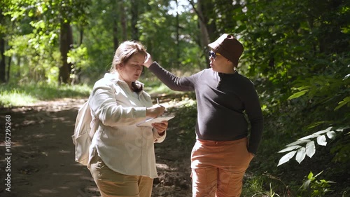 Mother and son swat away pesky mosquitoes and midges during walk in park. Risk of summer insect bites. Woman sketches nature during family nature walk.