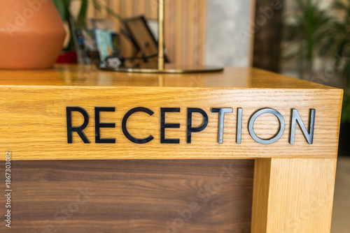 Hotel reception desk with modern lettering and wooden texture. First impression design, guest orientation, and structured hospitality service shaping welcoming interior spaces.