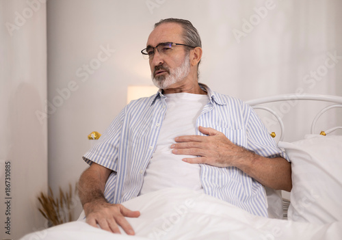 The elderly man, slumped on his bed, was exhibiting signs of anxiety, possibly due to illness, a heart attack, chest pain, or a medical emergency.