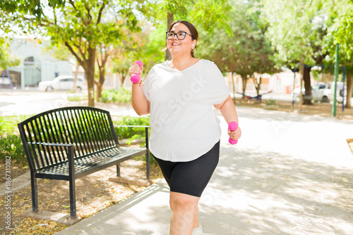 фотографія Happy plus size woman exercising outdoors, happy and confident, walking with dum