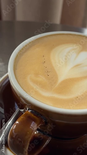 Smooth motion of a hand lifting and placing a steaming coffee cup on a cafe table, ideal for lifestyle, beverage ads, or relaxation content.