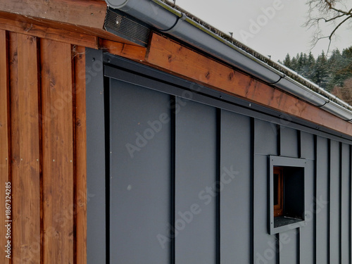 The dark panels are a style called Standing Seam Metal Siding, which is popular for its sleek lines and durability.Modern Cabin or Scandinavian architecture.