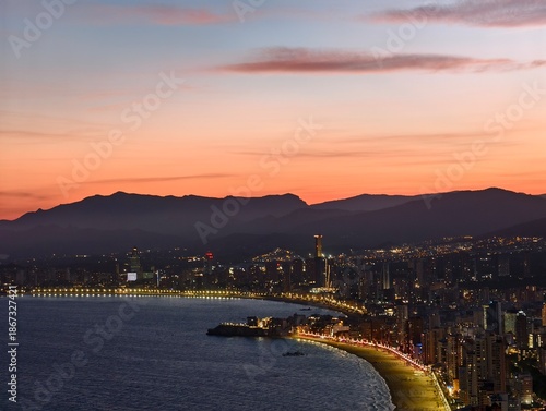 stunning coastal panorama, dusklit bay meets mountain range, drone captures serene seaside skyline