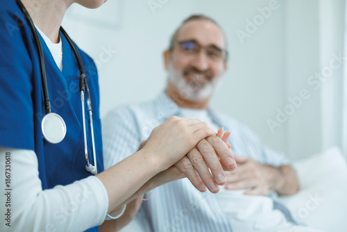The doctor shaking hands with the elderly man demonstrates care and encouragement for the patient. This image conveys themes of healthcare, trust, empathy, compassion, hope, and kindness.