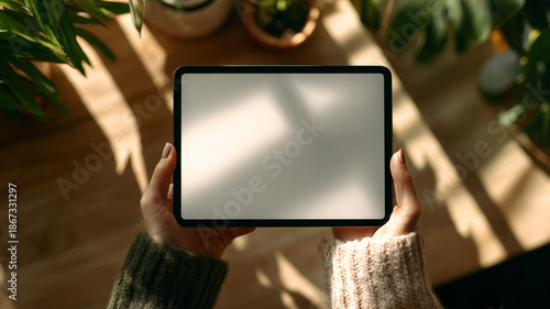 female hand holding blank tablet mockup, modern workspace desk background
