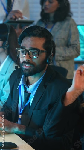 Customer service agent with headset discussing with colleague at call center office. Technical support, telemarketing, work collaboration. consulting service. Group working overtime.