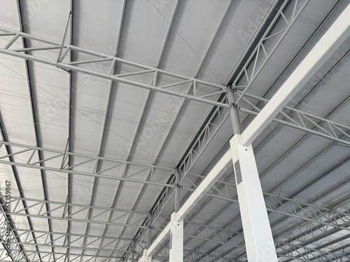 Interior view of an industrial warehouse roof featuring steel trusses, metal beams, and insulated roof panels, showing modern construction, strength, and clean structural design.