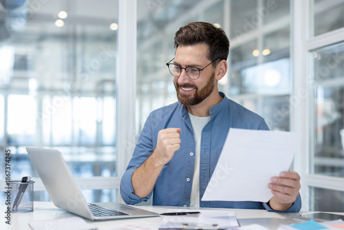 Fotografie Happy man in glasses celebrating business achievement, reading positive results