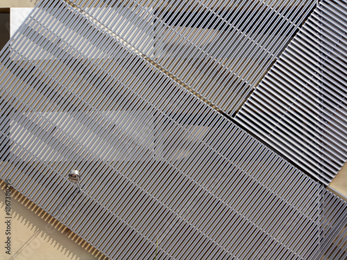 Building exterior wall facade with aluminium cladding in diagonal repetitive pattern in silver grey. and a wall street light.
