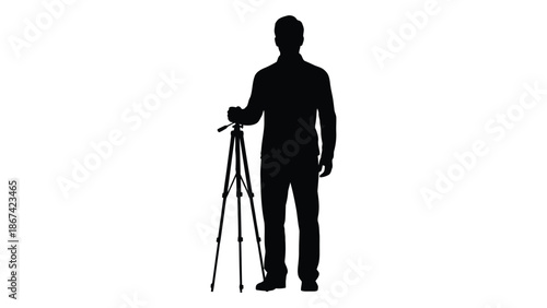Silhouette of a man standing with a tripod on a white background