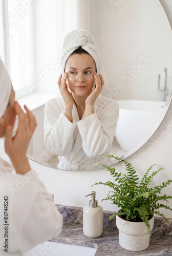 Woman applying under eye patches during morning skincare routine in modern bathroom