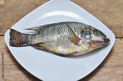 Wallpaper Mural Fresh Whole Tilapia Fish on White Plate Wooden Background Torontodigital.ca