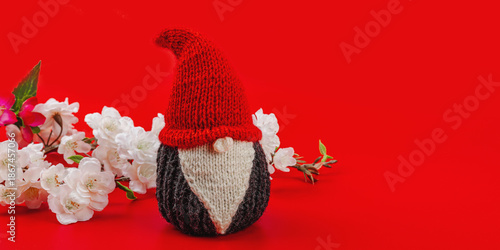 Minimalist spring greeting card with knitted gnome and blooming cherry branches