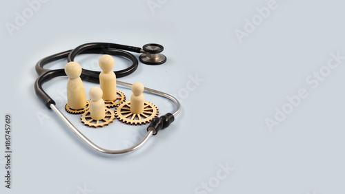 Group of wooden figures surrounded by stethoscope and gears symbolizing integrated healthcare system, teamwork, medical planning, and patient centered care concept.
