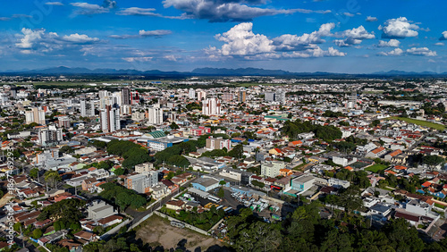 Drone footage of the city of São José dos Pinhais, located in the dynamic metropolitan region of Curitiba, on a day with a blue sky and some clouds, showing the central area.