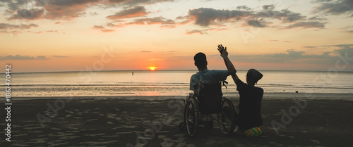 Cinematic scene of wheelchair user and caregiver watching beautiful sunset at the beach, concept of freedom, accessible tourism, inclusion and emotional family connection.