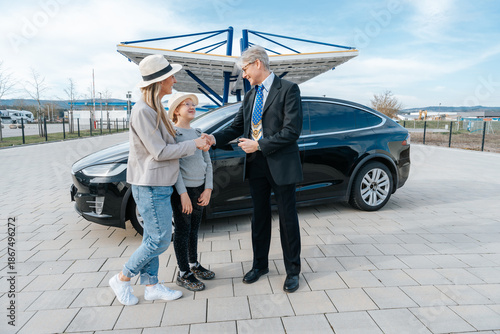 Car salesman sells a used electric car to a woman and her daughter highlighting trust, family decision making, and sustainable mobility