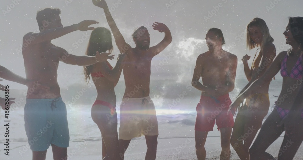 Fototapeta premium Laughing group of eight adults raising arms and talking on wet sand by ocean, wearing swimwear