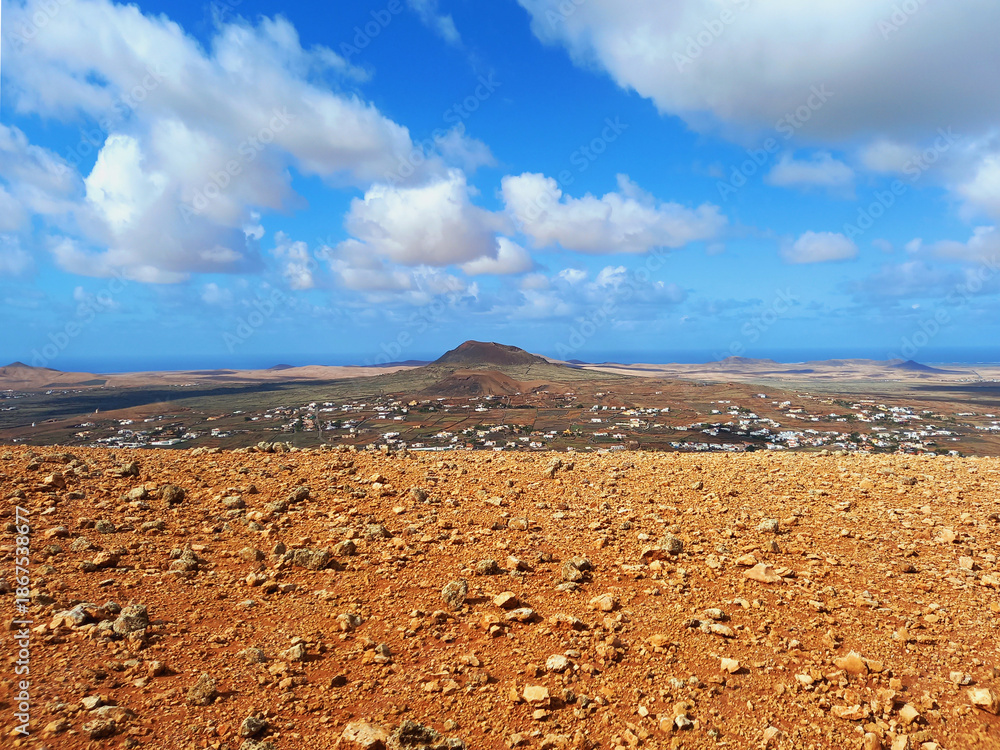 Fototapeta premium volcanic landscape. Desert area with stones, rocks and sandstone and silhouette of volcano slopes on the horizon. Landscapes and extreme nature.