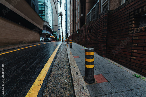 Narrow urban street in Seoul with wet asphalt and modern buildings