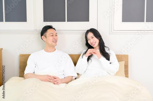 夜の寝室で笑顔で会話をする日本人男女