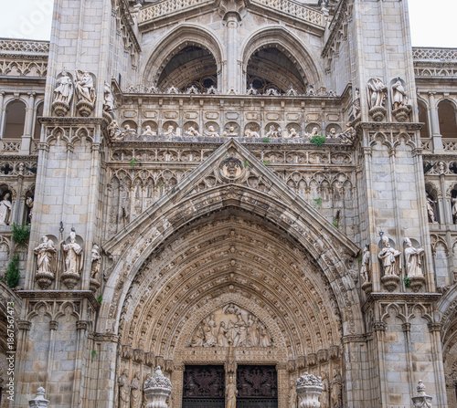 Detailed view of the intricate stone carvings and religious statues on the facade of the historic Toledo Cathedral in Spain.