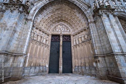 Intricate stone carvings and sculptures decorate the grand arched entrance of the historic Toledo Cathedral in Spain.