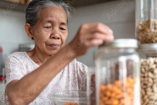 Senior Woman Organizing Kitchen Jars: Focus on Food Storage and Home Organization.