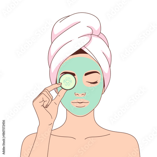 A woman with a green face mask and a towel on her head, holding a cucumber slice over one eye for a relaxing spa treatment.