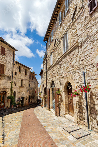 Streets of Assisi, a medieval town in Umbria, Italy, adorned with flowers and historic stone architecture