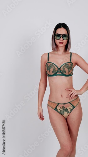 Woman in green embroidered lingerie set posing.