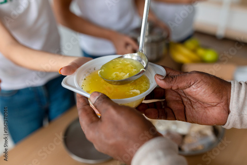 Fotografija Young people engage in a charitable activity by serving hot soup to homeless individuals at a donation center