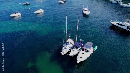 Aerial view of three sailboats rafted together in crystal clear turquoise water in Malta.