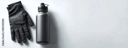 Black Water Bottle and Gloves Set on a White Surface for Sports and Outdoor Activities