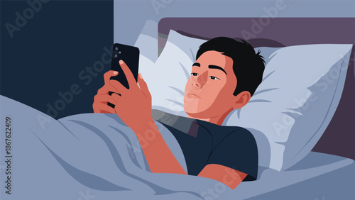 Young man lies in bed late at night while using his smartphone and looking at the screen in a dark and quiet bedroom.