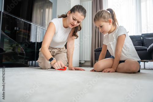 Photos Mother and daughter playing with toy cars on floor at home
