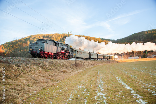 Small steam train visible in the distance while crossing a peaceful rural winter landscape