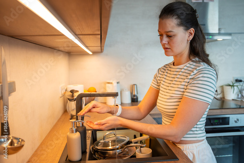 Εκτύπωση καμβά A woman washes her hands at a kitchen sink while preparing food at home
