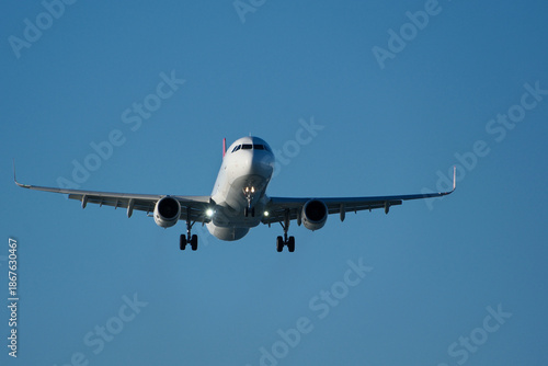 Passenger Jet Landing Approach in Bright Blue Sky. Commercial Airplane on Final Approach to Runway Under Clear Blue Sky