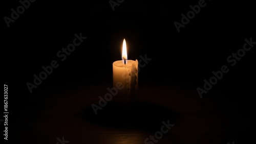 One burning candle providing light in the darkness. Isolated on a black background for concepts of hope, faith, and remembrance