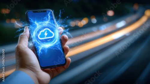 Cloud sync lightning icon on smartphone screen held by hand at night with motion blur road lights