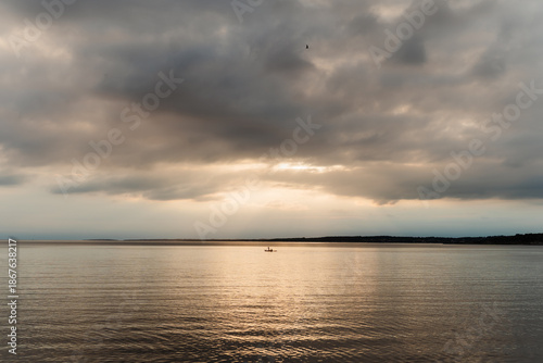 Dramatic summer evening view over the sea with a lone kayak and mainland horizon, Swedish West Coast