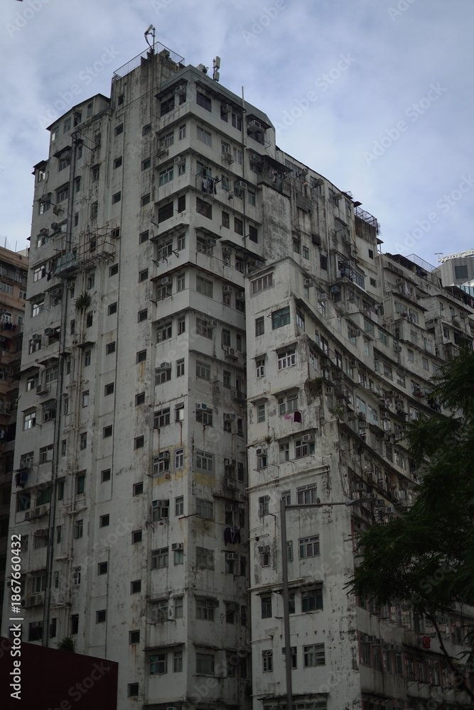 Fototapeta premium Hong Kong street life: Traditional tram passing the legendary Monster Building. Authentic urban landscape, dense housing architecture, and cinematic city atmosphere. Ideal for editorial or commercial.