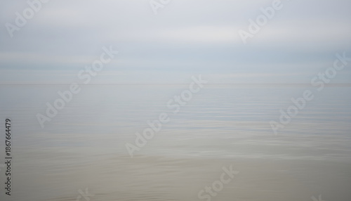 Calm ocean water meeting foggy horizon sky