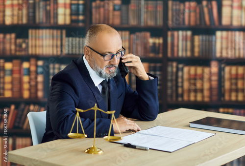 Foto Senior attorney giving legal advice, talking on phone in law firm office